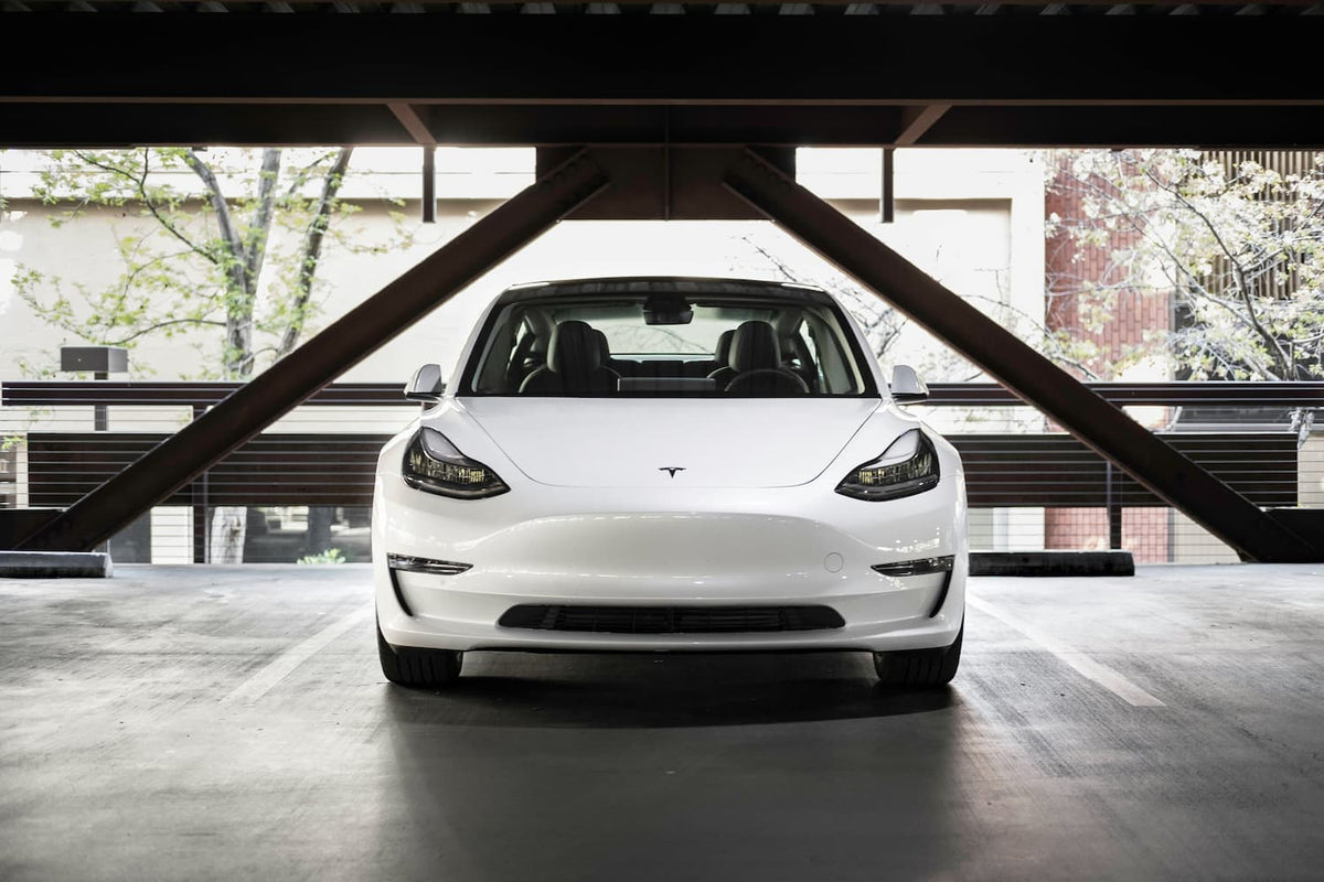 Biala Tesla zaparkowana w nowoczesnym parkingu, widok z przodu i minimalistyczny wyglad.