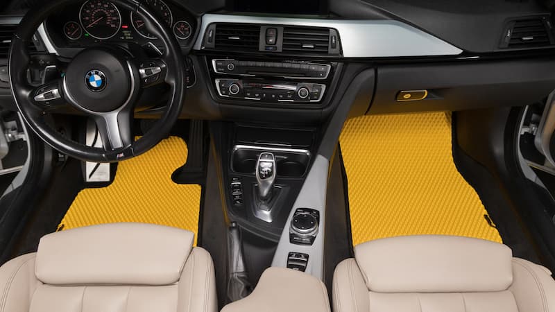 Żółte dywaniki Prime EVA zamontowane z przodu wnętrza BMW.