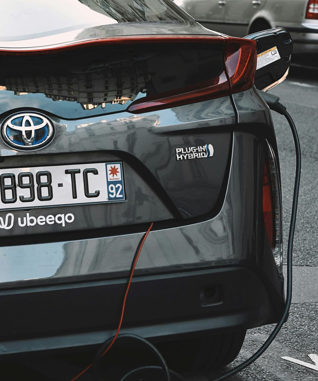 Toyota plug-in hybrid podczas ładowania w mieście podkreślający ekologiczną mobilność.