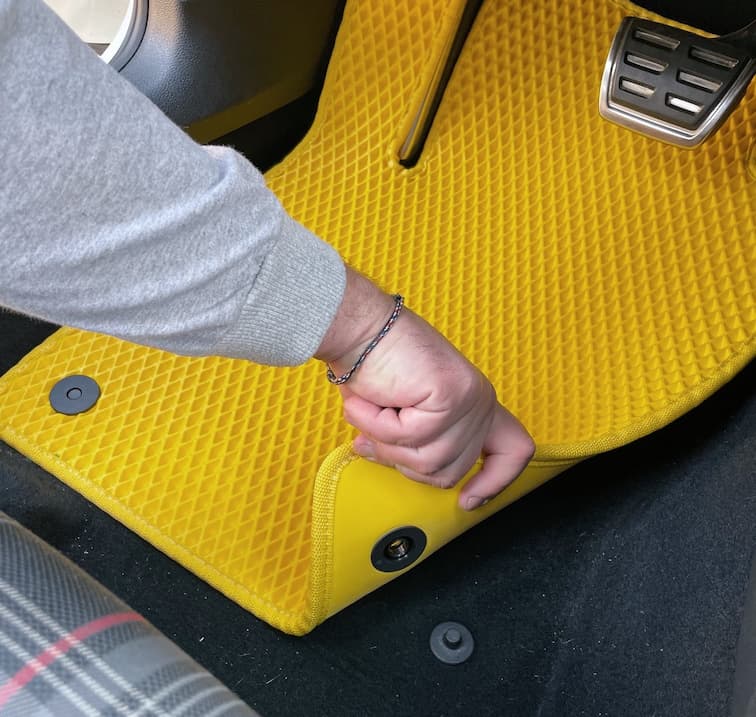Dłoń mocuje żółtą matę EVA klipsem w miejscu kierowcy.